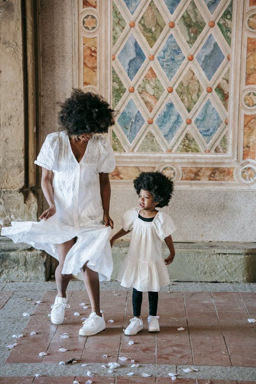 A Woman in White Dress Dancing Beside a Girl