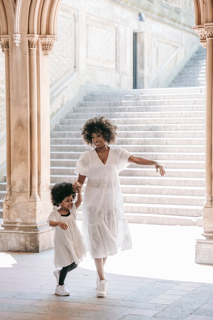 A Happy Woman Holding Hands While Walking With Her Daughter