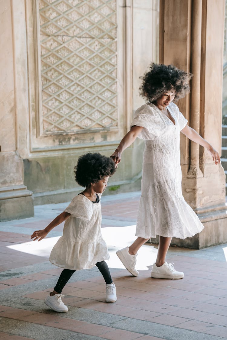 Mother And Child In Their White Dresses Dancing On The Floor