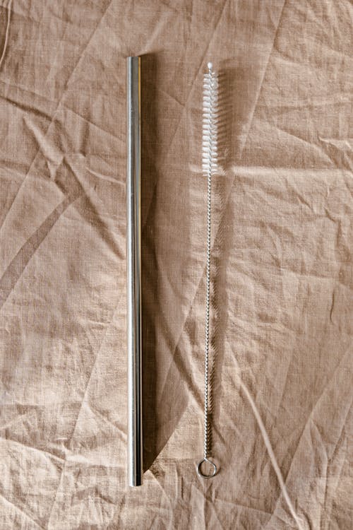 Stainless Steel Straw and Brush on Brown Textile