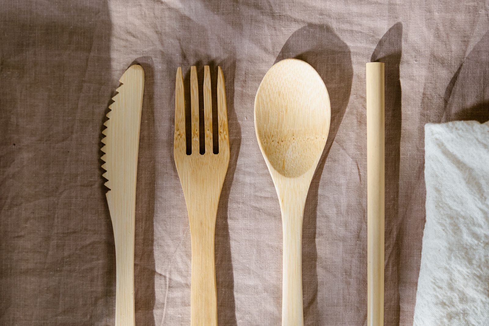 Minimalist wooden cutlery set displayed on a brown textured cloth, perfect for eco-friendly dining concepts.