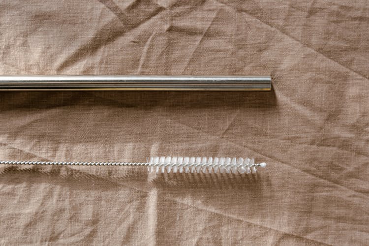 Close-up Of A Metal Straw And A Cleaning Brush