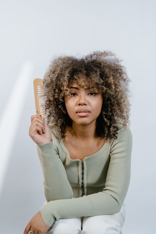 Woman with curly hair holding a wooden comb