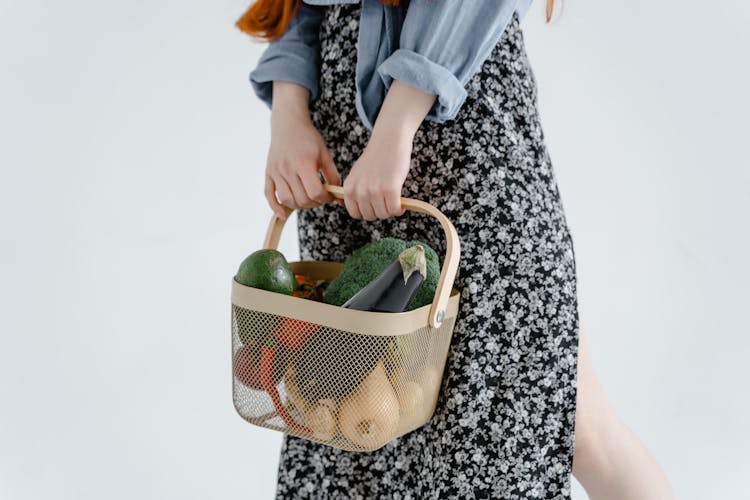 A Person In Floral Dress Holding A Basket Of Fruits And Vegetables