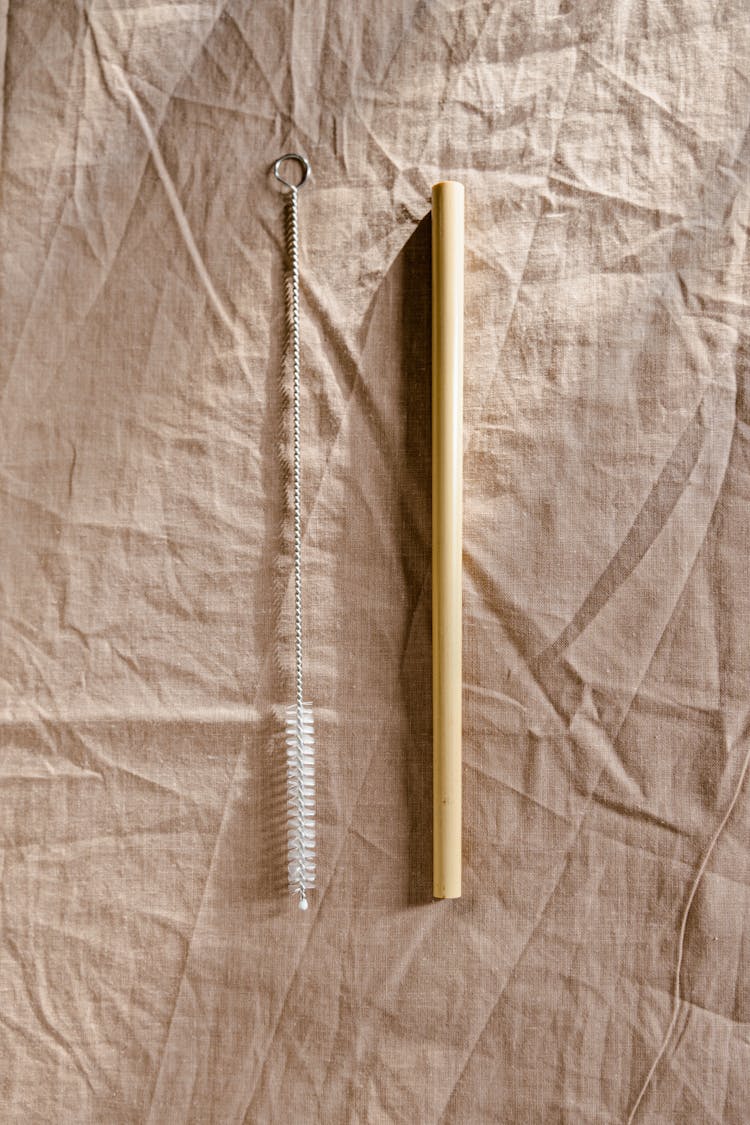 A Wooden Stick On Brown Textile Beside A Bottle Brush