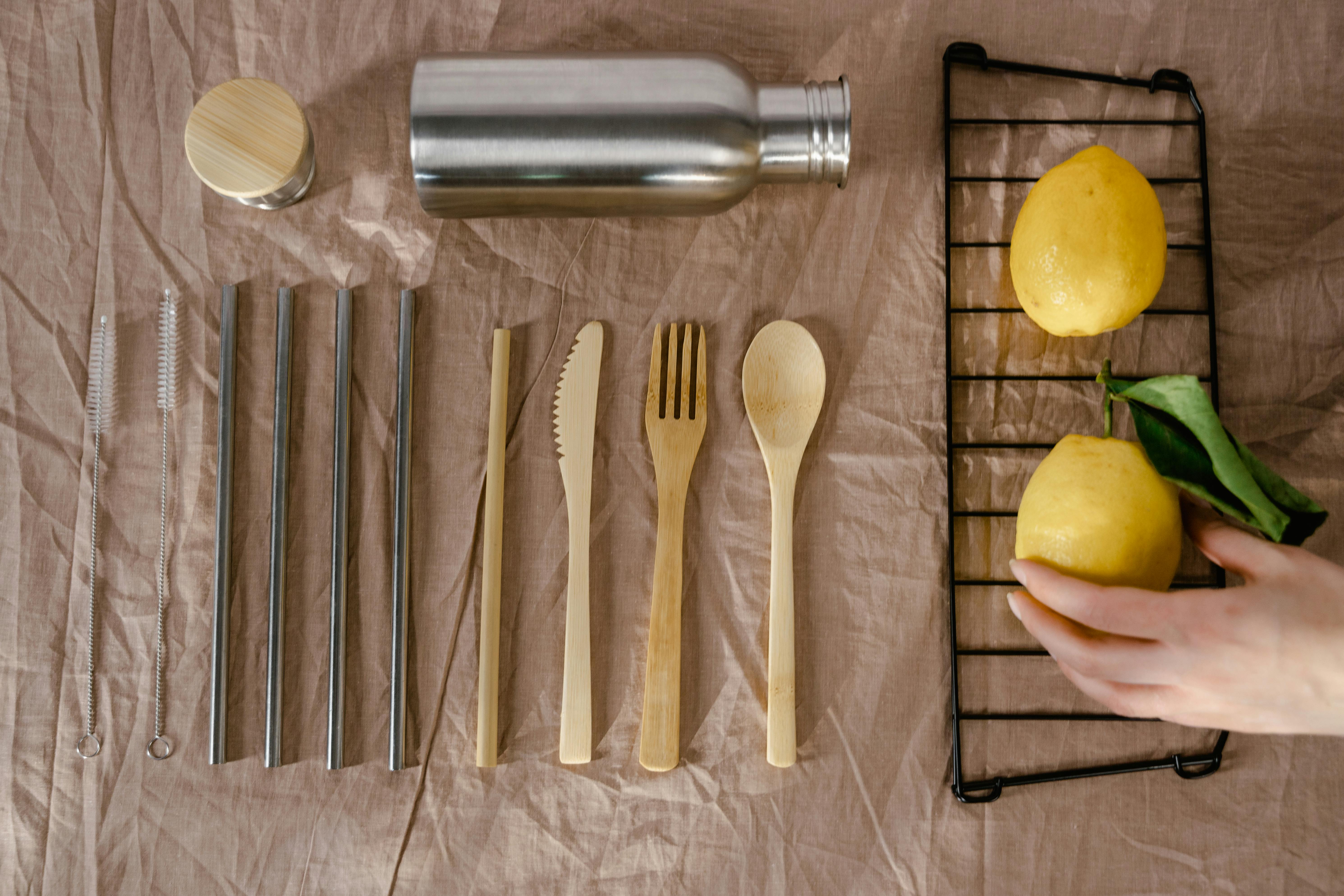 Zero waste eco-friendly utensils, lemon, steel straws on textile for sustainable living.