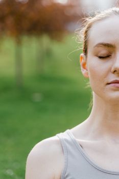 Peaceful woman meditating outside with eyes closed, surrounded by nature.