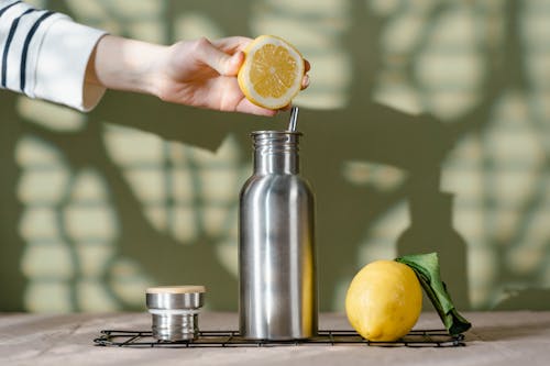 Free Person Squeezing Lemon on Stainless Steel Water Bottle Stock Photo