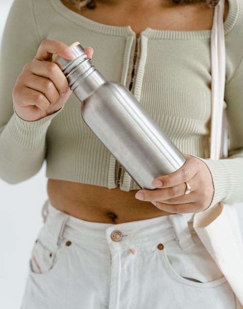 Free Person holding a reusable stainless steel water bottle promoting eco-friendly and zero waste lifestyle. Stock Photo
