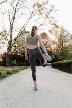 A woman in activewear stretches in a park setting, preparing for exercise.