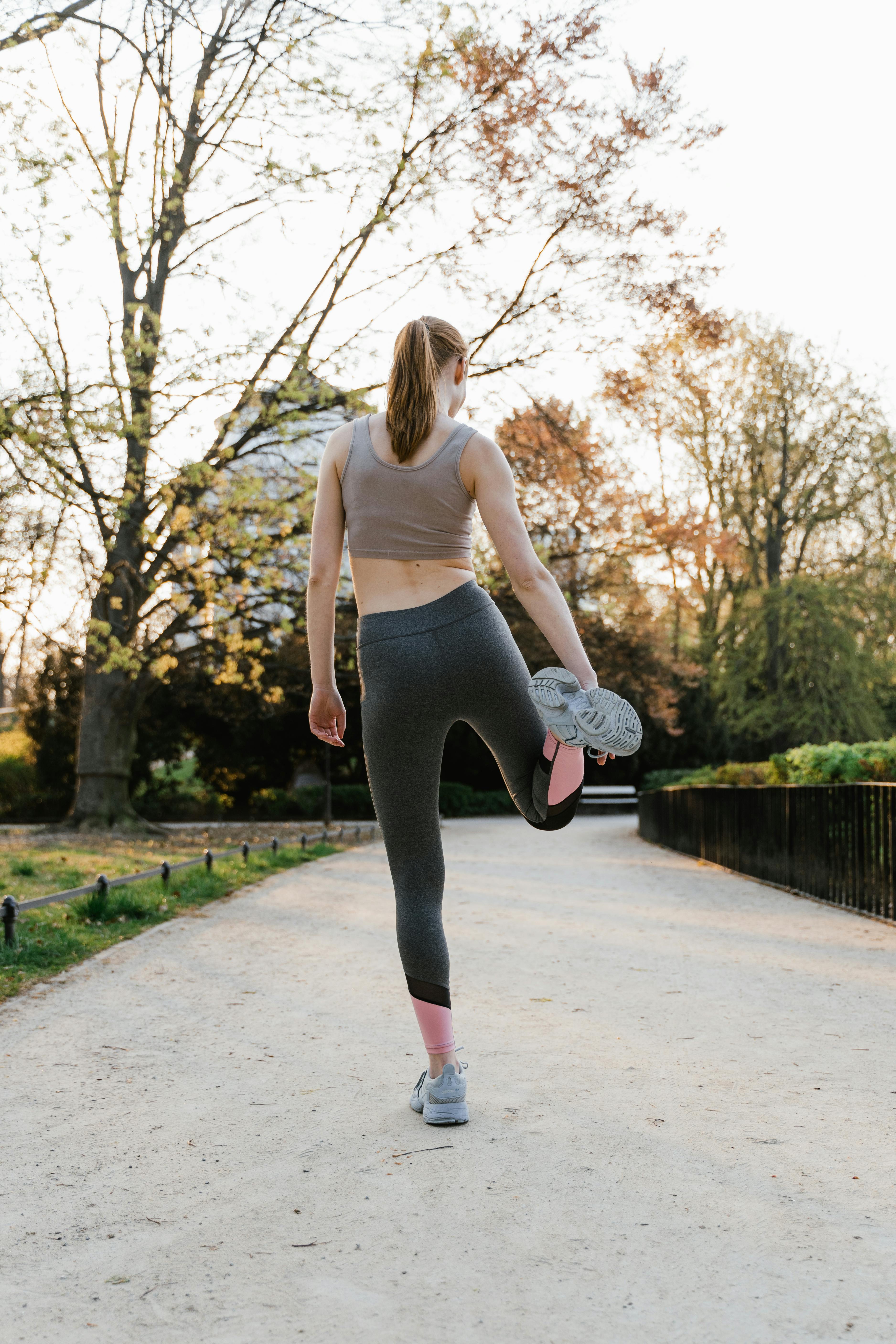 Back View of a Woman in Activewear Stretching her Leg at a Park · Free Stock  Photo