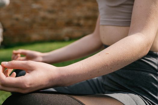 Close-up of a woman practicing yoga outdoors in the sunlight, focusing on mindfulness and relaxation.