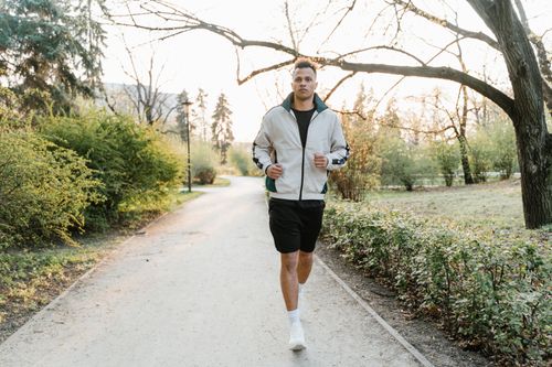Free Adult male jogging on a scenic park path, embracing fitness in the fresh morning light. Stock Photo