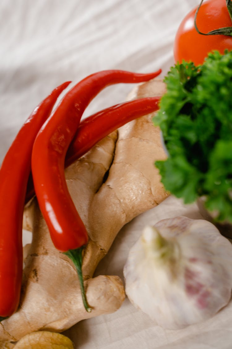 Pieces Of Chili Peppers On A Ginger Beside A Head Of Garlic