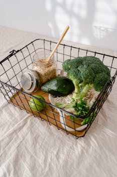 Fresh broccoli, avocado, and oats ready for healthy meal preparations in a wire basket.