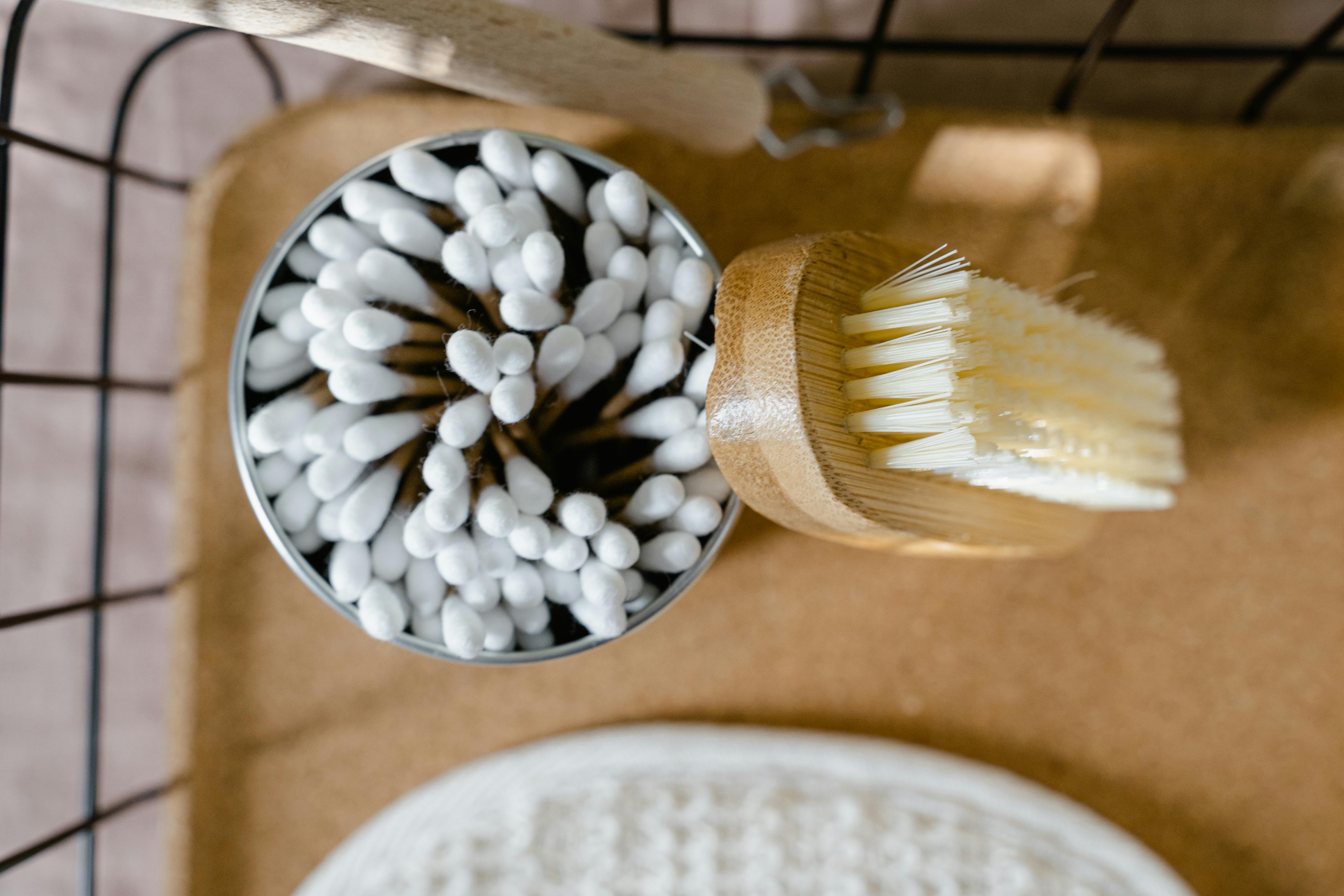Flat lay of eco-friendly cotton swabs and a wooden cleaning brush in a natural setting.