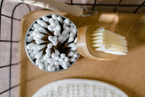 A Wooden Bush Leaning on a Round Container Filled with Cotton Swabs
