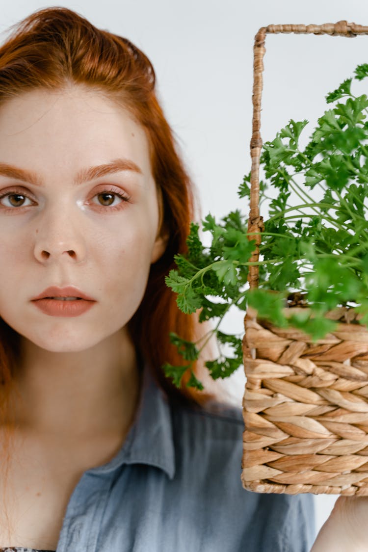 Woman Beside A Basket Of Leafy Vegetable In Close Up View