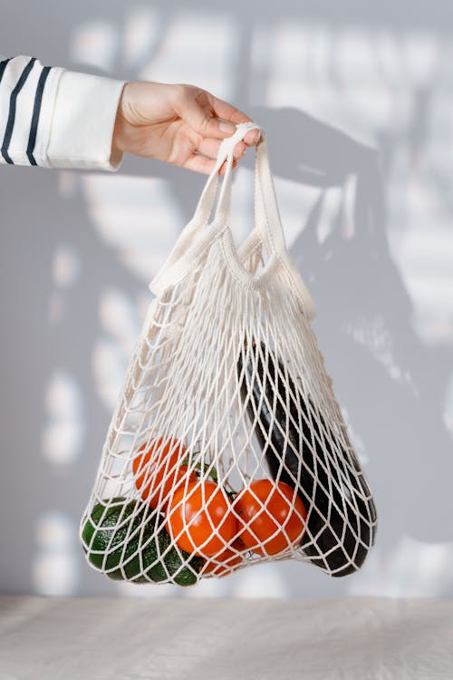 Person Holding White Net Bag with Fruits