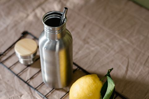 Steel water bottle with a straw lid next to a lemon
