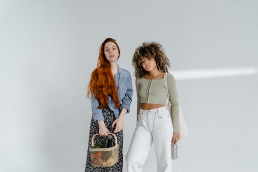 Diverse women posing with eco-friendly items and fashion on a white background.