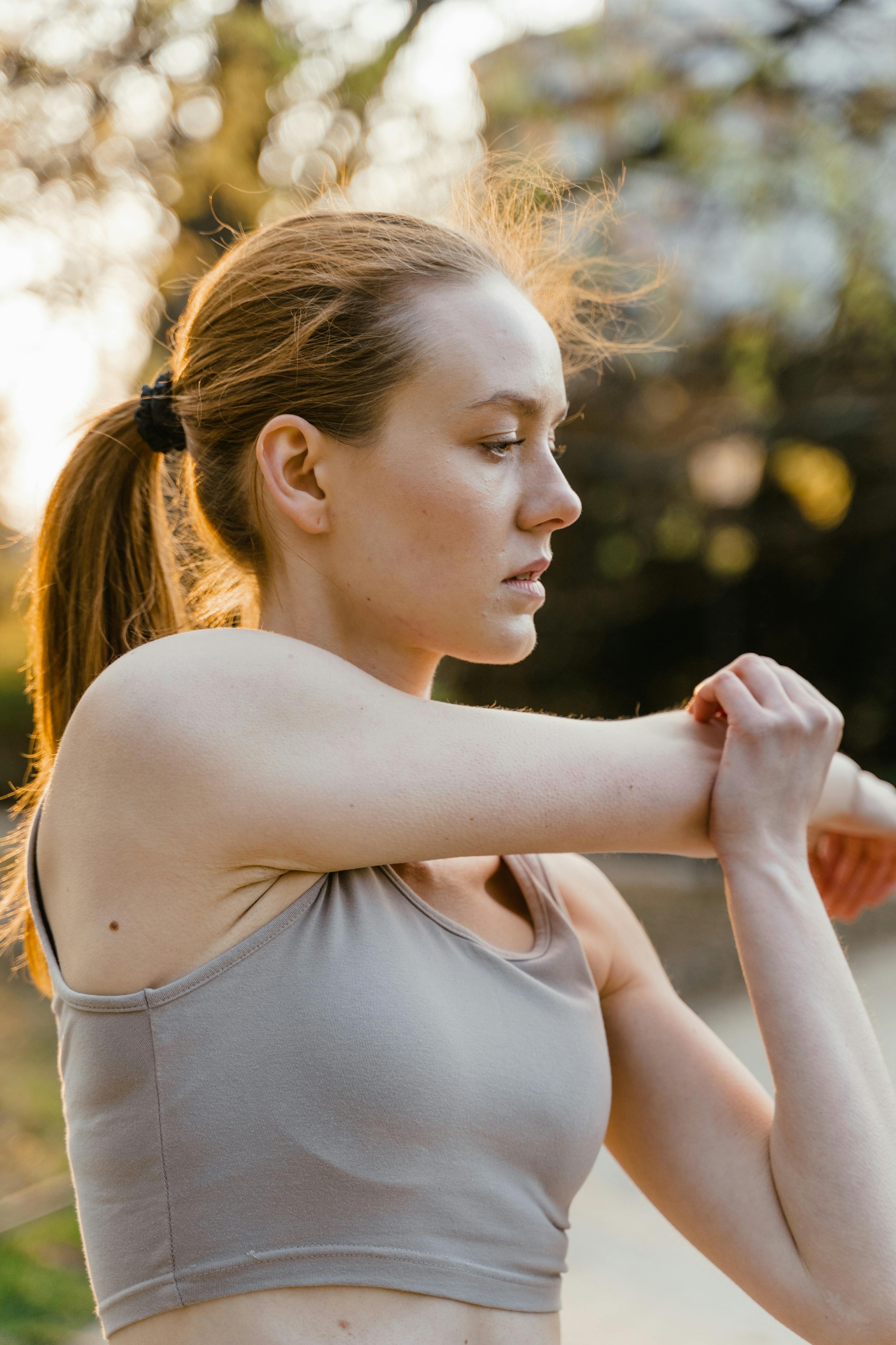 A smiling person exercising outdoors, sunny day, fitness tracker, healthy lifestyle, determined expression.