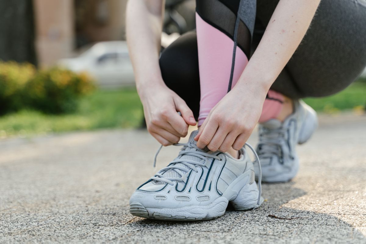 Person tying running shoe laces before going for a run in the park