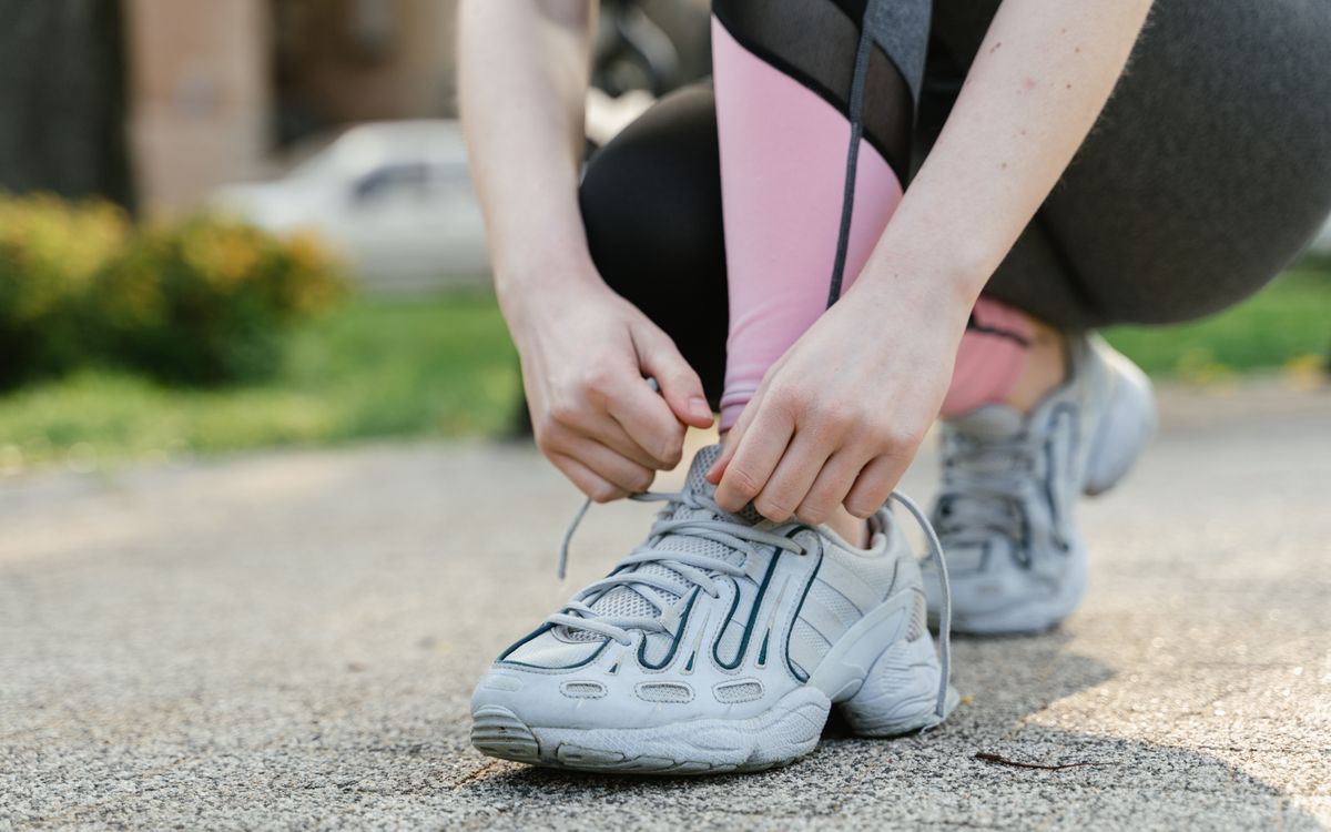 Woman tying shoelaces on sneakers before a run in the park.