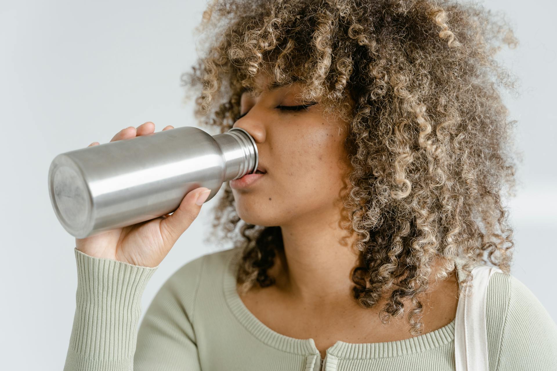 A Woman Drinking from Silver Bottle