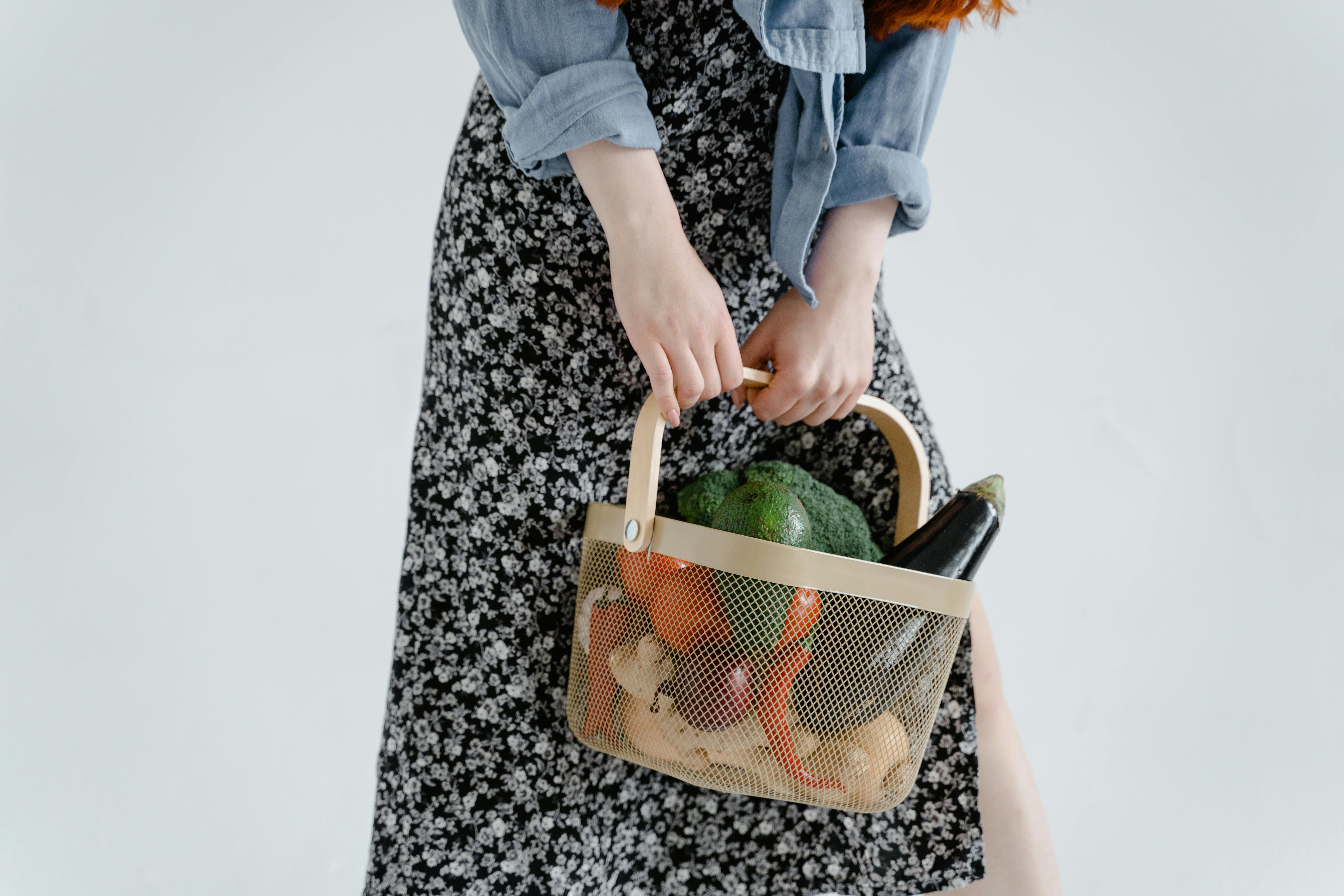 a person holding a basket full of fresh vegetables and fruits