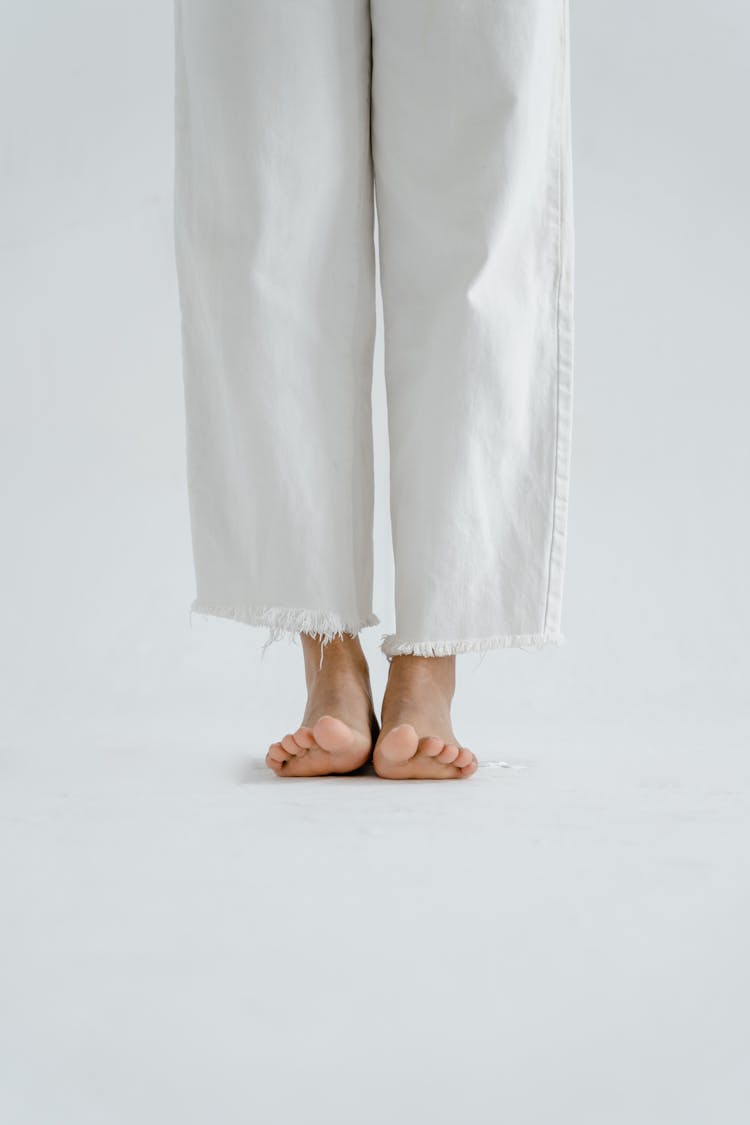 A Barefooted Person Wearing White Jeans