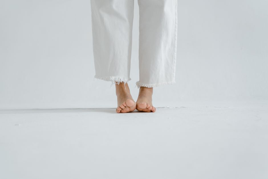 pexels photo 7880063 Close-up of bare feet in white jeans on a white minimalist background.