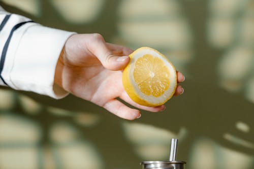 Close-Up Shot of a Person Holding a Slice of a Lemon