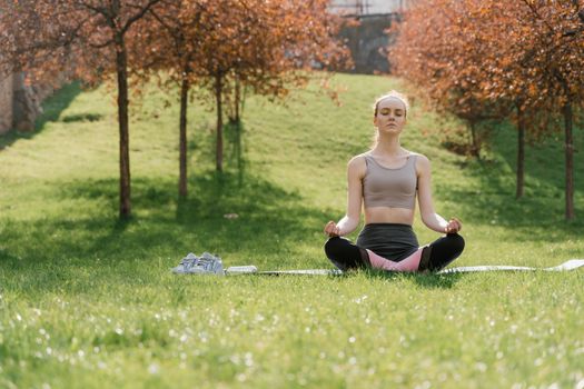 Woman practicing meditation in a sunny park, enhancing wellness and mindfulness.