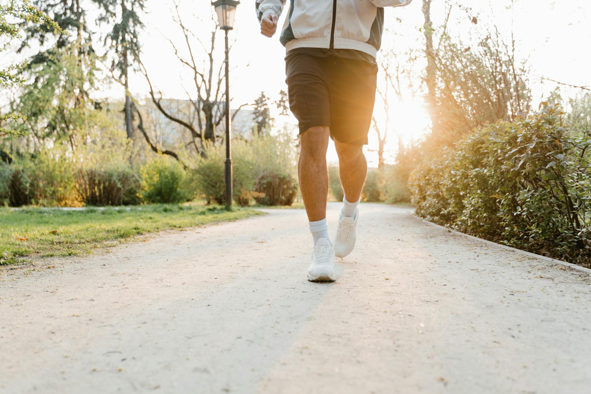 A person jogging on a park pathway during sunrise, promoting fitness and outdoor activity.