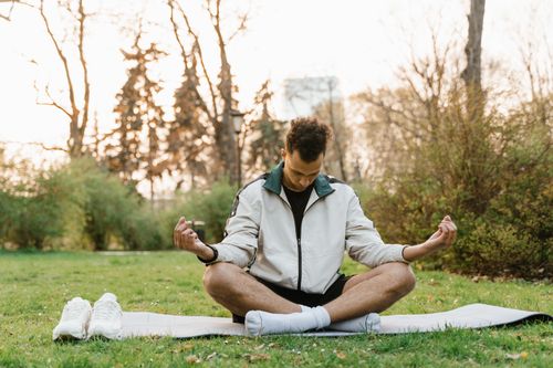 Free A man practices meditation in a serene park, embodying relaxation and mindfulness. Stock Photo