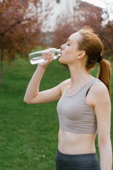 Woman in activewear drinking a bottle of water