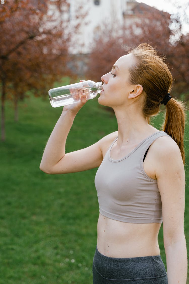 Woman In Activewear Drinking A Bottle Of Water 