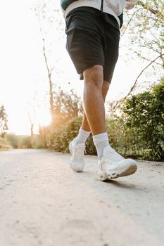 A runner walks on a sunlit path, highlighting active lifestyle and footwear.