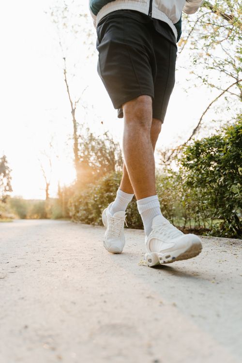 Free A runner walks on a sunlit path, highlighting active lifestyle and footwear. Stock Photo