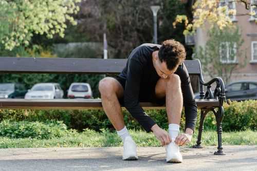 Free A man in activewear ties his shoes on a bench, ready for exercise. Stock Photo