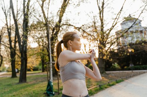 Free A woman in activewear stretches in a scenic park at sunset, promoting a healthy lifestyle and wellness. Stock Photo