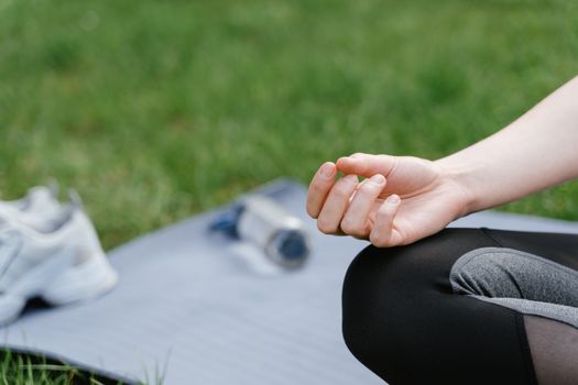 Close-up of a woman meditating outdoors on a mat. Focus on tranquility and mindfulness.