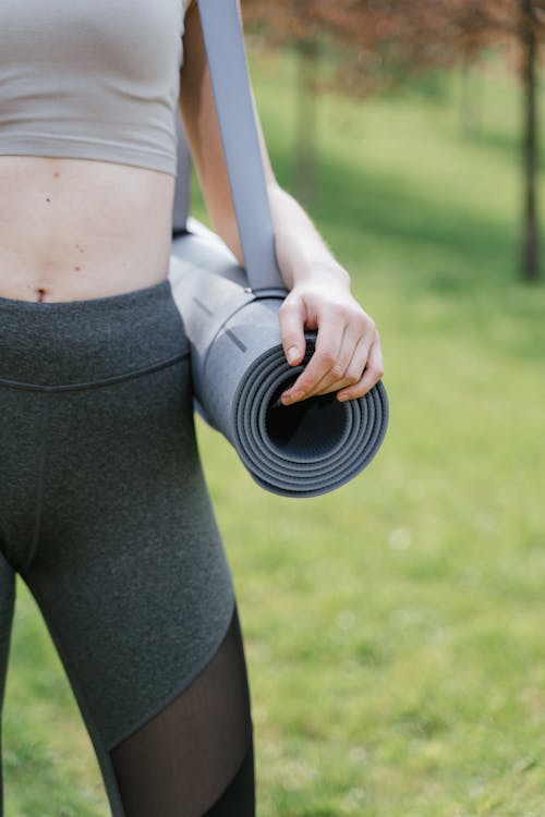 A Person in Gray Leggings Holding Gray Yoga Mat