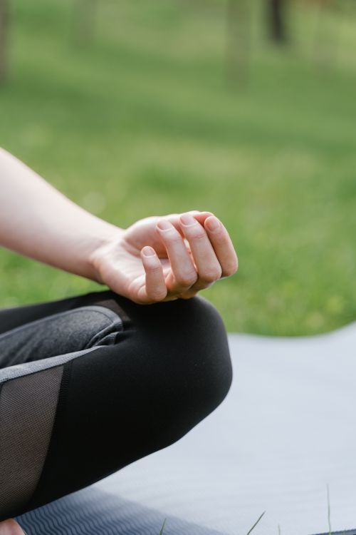 Free Close-up of a person meditating outdoors on a yoga mat with focus on hand gesture. Stock Photo