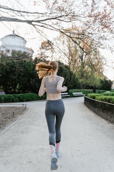 Back view of a woman jogging in a park, promoting a healthy lifestyle.