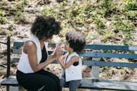 Mother and Child with Same Outfits seated on a Wooden Bench