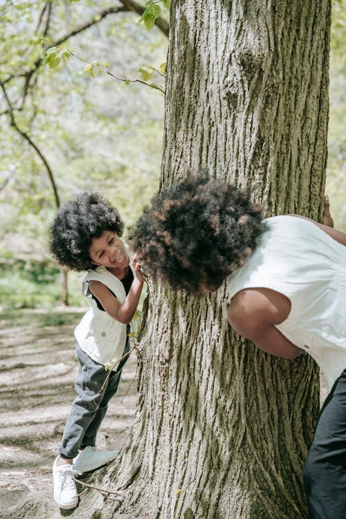 Free Mother and Child Playing Hide and Seek on a Tree Trunk Stock Photo