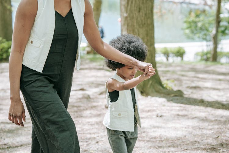 Mother And Child Walking Hand In Hand In The Park