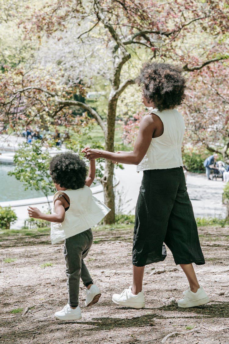 Mother And Child Walking Hand In Hand In The Park